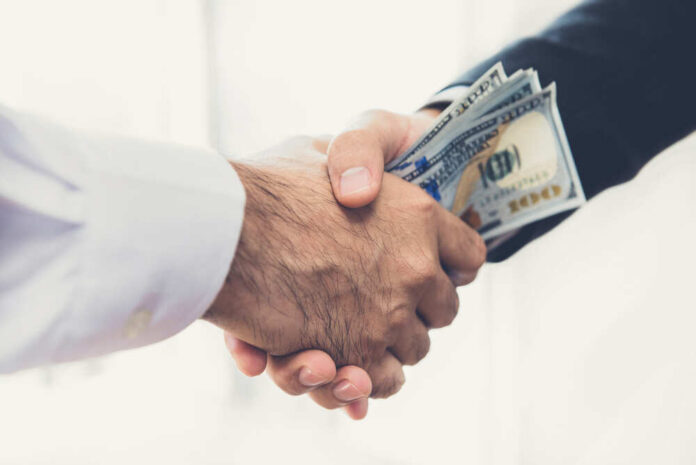 Businessmen,Making,Handshake,With,Money,In,Hands,-,Bribery,And