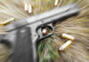Pistol and bullets on grass with motion blur effect.