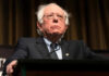 Bernie Sanders in suit speaking at podium.