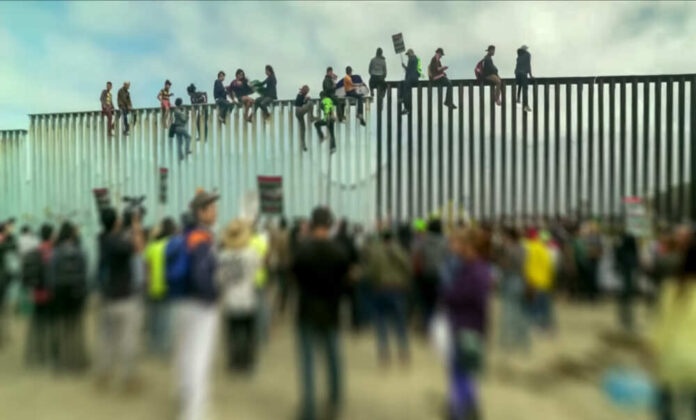 shutterstock_1229072281-1.jpg featured image People sitting on a border wall with crowd below.