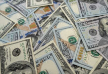 Scattered hundred dollar bills with Benjamin Franklin's portrait.