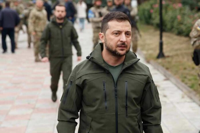 shutterstock_2204022829.jpg featured image Volodymyr Zelenskyy in military attire walking outdoors among others.