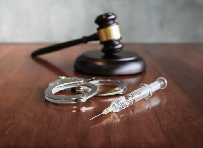 shutterstock_1126185632.jpg featured image Gavel, handcuffs, and syringe on wooden table.