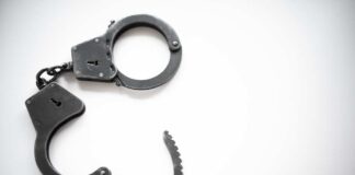 Open metal handcuffs on white background.