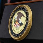 DOJ SUES – Four Blue Cities Under FIRE! Department of Justice seal on a podium.