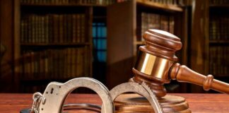 Wooden gavel and handcuffs on a table.
