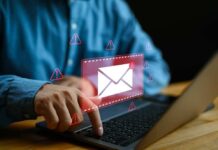 Person typing on laptop with mail warning icons.