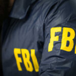 FBI Confirms – China Interfered In 2020! FBI agent in navy blue jacket.