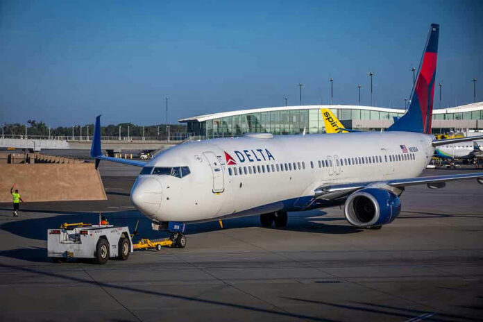 2121460637 Delta airplane being towed at airport terminal gate