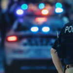 Police Officer Stands Near Patrol Car
