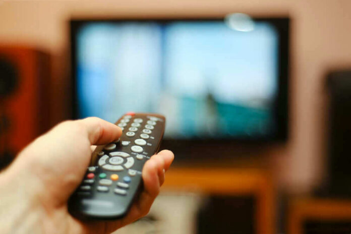 shutterstock_193018853.jpg Hand holding a remote control towards a TV screen
