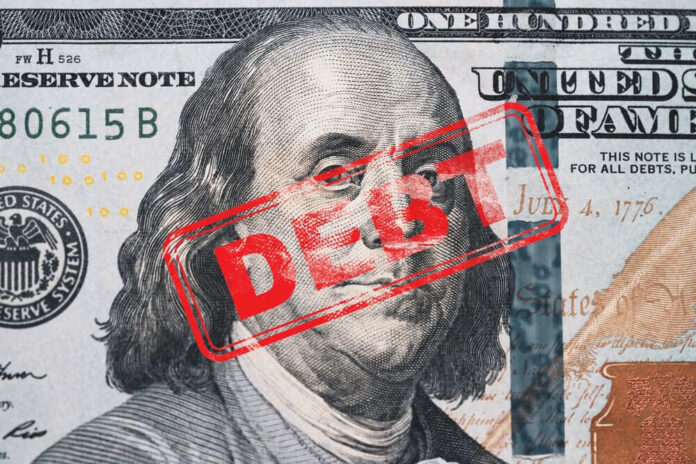 shutterstock_2407082349.jpg Hundred dollar bill with red debt stamp