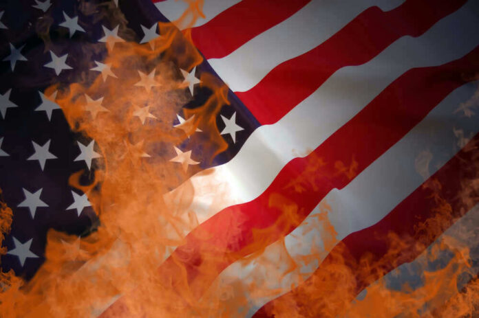 shutterstock_47429077.jpg American flag partially set on fire with orange flames
