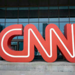 Red CNN logo in front of glass building