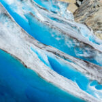 Blue glacier ice with crevasses and rocky surface