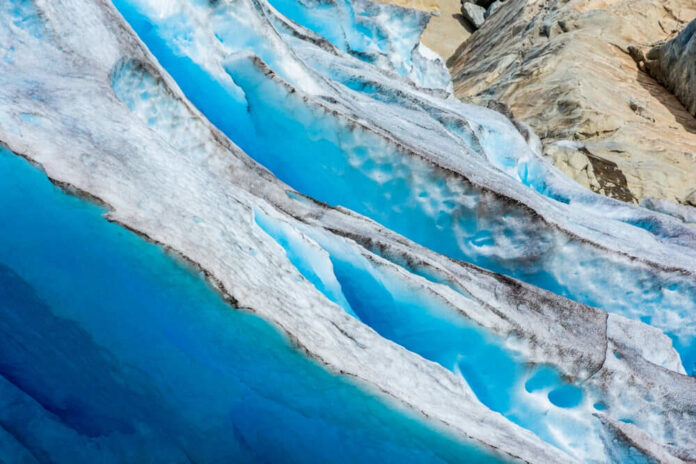 Blue glacier ice with crevasses and rocky surface
