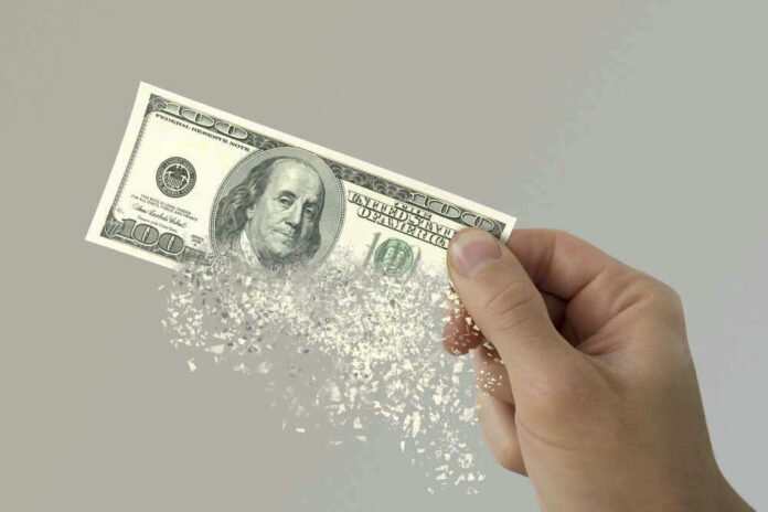 shutterstock_580278601.jpg Hand holding a disintegrating hundred dollar bill