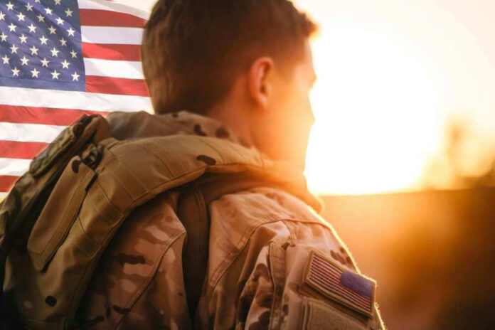 Soldier in camouflage facing American flag at sunset