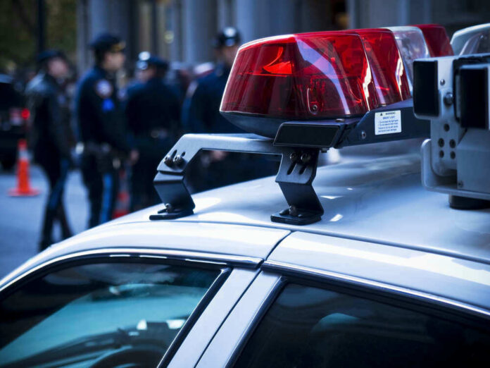 Police car roof with lights, officers in background