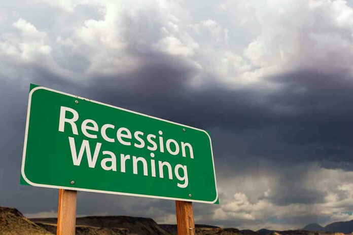 Recession Warning sign with dark, stormy clouds above.