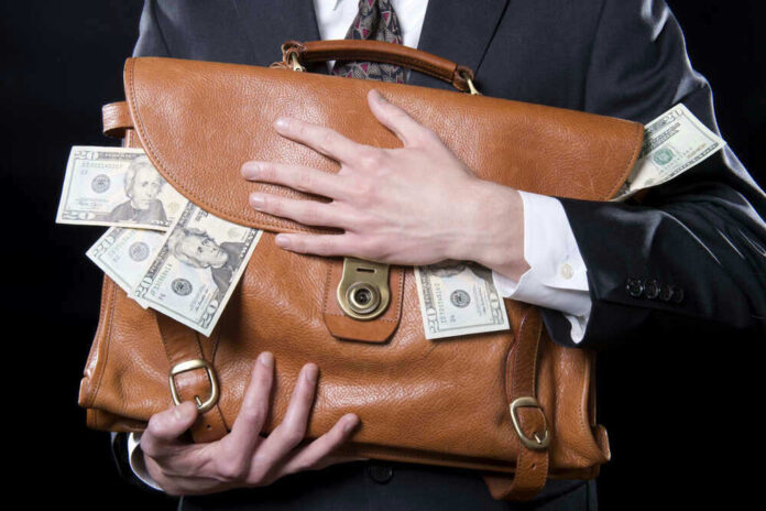 shutterstock_133129220.jpg Person holding briefcase with money protruding from it.
