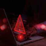 DATA BREACH Exposes Millions Warning symbol over laptop with user.