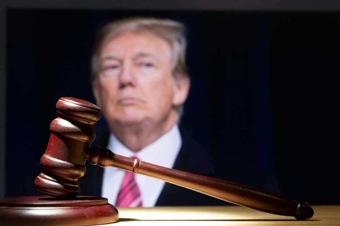 Gavel in foreground with Donald Trump in background.