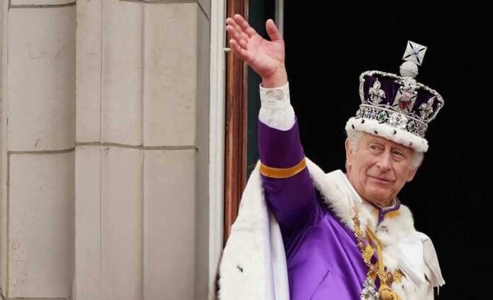 King Charles in royal attire waving from a balcony