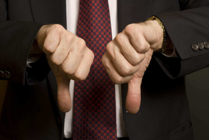 Two hands showing thumbs down in a suit