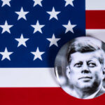 JFK Granddaughter’s SHOCKING Political Death Blow A black and white badge of John F. Kennedy on an American flag background