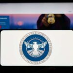 TSA $18 Fee Shocker Hits Travelers A hand holding a smartphone displaying the Transportation Security Administration logo