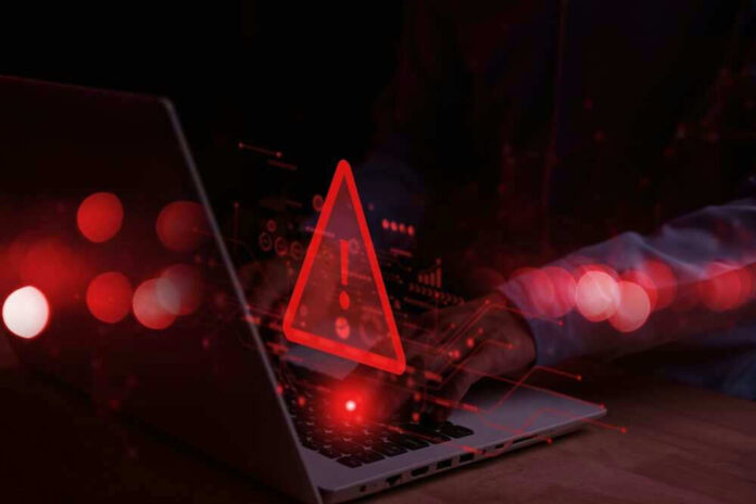 Warning symbol over laptop with user.