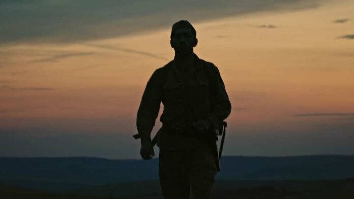Silhouette of a soldier walking against a sunset backdrop
