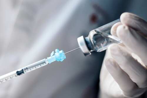 A healthcare professional preparing a syringe from a vial
