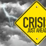 Chaos Now Threatens Thanksgiving Yellow sign reading Crisis Just Ahead with stormy sky