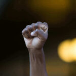 Actor CONFRONTS Kidnapper — Saves Teen Girl Raised fist in defiant gesture, blurred background.