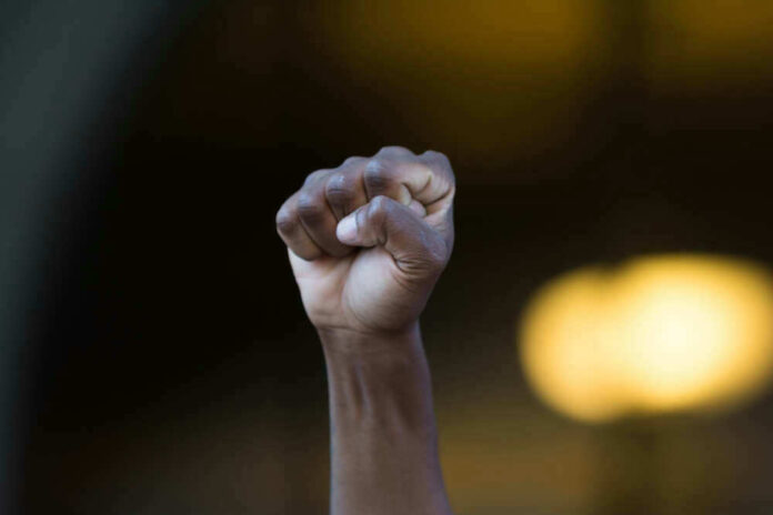 Raised fist in defiant gesture, blurred background.
