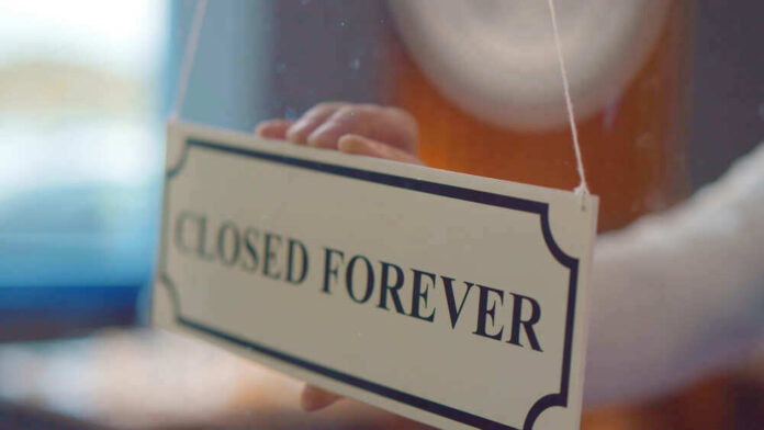 shutterstock_1836658408.jpg Closed forever sign being placed on window.
