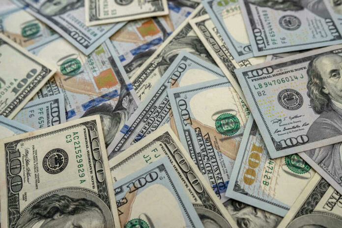 Scattered hundred dollar bills with Benjamin Franklins portrait.