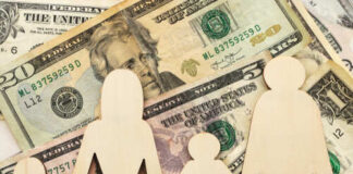 Wooden figures representing a family on a background of US dollar bills