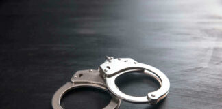 Metal handcuffs on a dark textured surface.