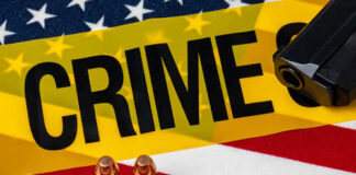 A gun and bullets on an American flag with a crime scene marker