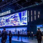 Samsung exhibition booth with a large digital display and attendees