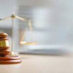 A wooden gavel and scales of justice on a desk