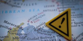A close-up of a map showing Venezuela with a yellow warning sign
