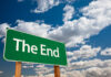 A green road sign that reads 'The End' against a blue sky with clouds
