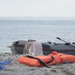 An inflatable boat on the beach with a life jacket and clothes nearby