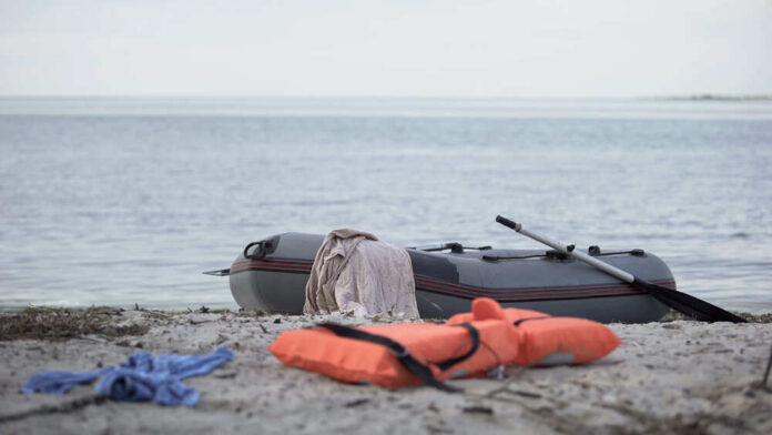 An inflatable boat on the beach with a life jacket and clothes nearby