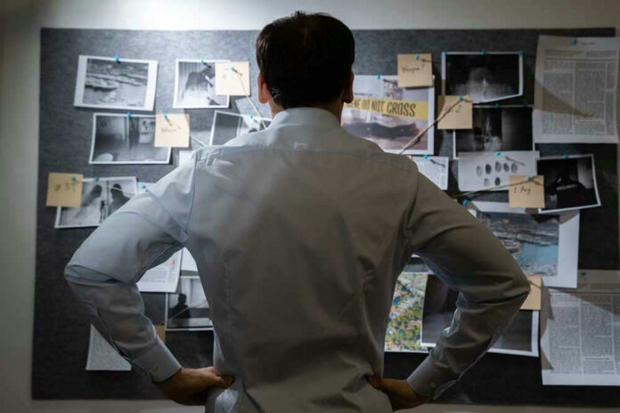 shutterstock_2140725125.jpg Man examining investigation board with photos and notes.