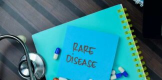 A notepad with 'RARE DISEASE' written on it, surrounded by various pills and a stethoscope